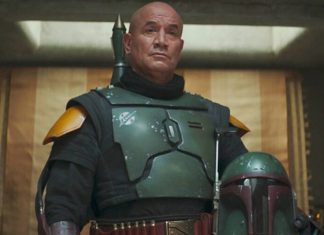 A medium shot of Temuera Morrison as Boba Fett, wearing his green and black Beskar armor without a helmet, standing in his palace on Tatooine.