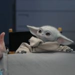 A close-up of the Grogu animatronic puppet sitting at a roundtable during a promotional interview for The Mandalorian and Grogu.