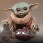 A highly detailed, 1:1 scale Grogu Life-Size Collectible Figure by Hot Toys, featuring a realistic head sculpt, fabric robes, and a leather-like pouch filled with accessories like a magnetic rondel and grav charges.