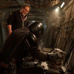 Jon Favreau stands behind Din Djarin and Grogu on a practical set for the upcoming Star Wars movie.