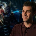 Editor Adam Gerstel, who joined the Star Wars: Starfighter production team, pictured during an interview with a cinematic robot background.