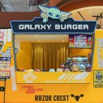 A vibrant yellow "Galaxy Burger" interactive booth designed like the Razor Crest ship, featuring a cartoon Grogu on top and Star Wars-themed menu items at the AIRSIDE Hong Kong exhibition.
