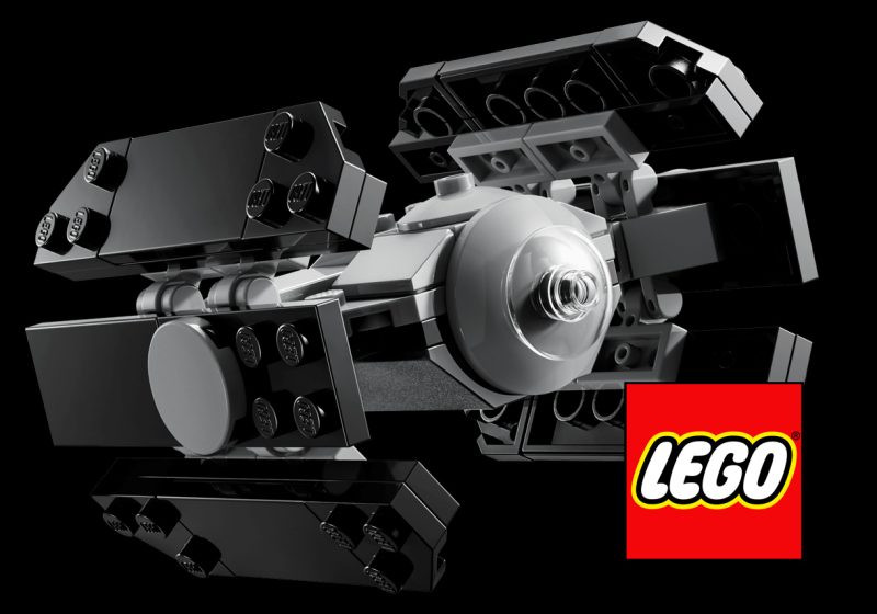 A micro-scale LEGO TIE Advanced starfighter model featuring grey and black bricks with a transparent cockpit dome and the red LEGO logo in the corner.