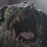 Close-up of a Mantellian Savrip snarling with its mouth wide open, showing sharp teeth and a pink tongue, as seen in The Mandalorian and Grogu TV spot.