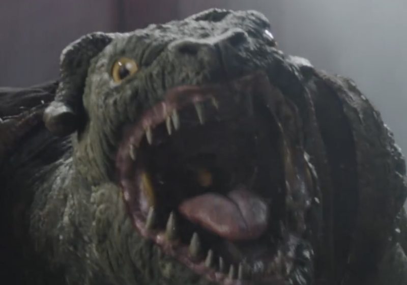 Close-up of a Mantellian Savrip snarling with its mouth wide open, showing sharp teeth and a pink tongue, as seen in The Mandalorian and Grogu TV spot.