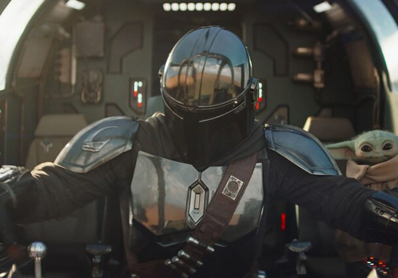 The Mandalorian and Grogu sitting in the cockpit of their starship, the Razor Crest, preparing for flight.