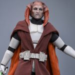 A 1/6th scale Hot Toys Saesee Tiin collectible figure wearing weathered white Clone armor and a dark brown Jedi robe, holding a glowing green lightsaber.