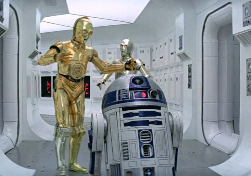 C-3PO and R2-D2 standing in a white Tantive IV hallway from Star Wars: A New Hope.